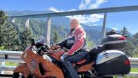 Privatfoto af Liselott Blixt, formand for Psoriasisforeningen, der sidder på sin røde motorcykel foran et bjerglandskab. 