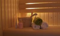 Billede viser hjørne af en sauna, en bænk med nogle håndklæder, en balje og nogle produkter, en luksuriøs opstilling.