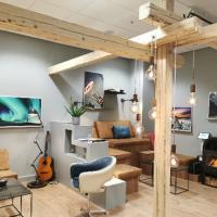 Billede af lokalet NCAS' ungegruppe mødtes i. Hyggeligt lokale med bjælker, afdæmpet belysning, hyggelamper, kunst på vægge, sofa og guitar.